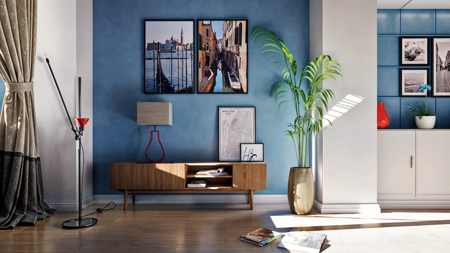 Комната в золотисто-голубых тонах, тумбочка на высоких ножках, напольная ваза с растением, постеры на стене, настольная лампа с квадратным абажуром, книги на полу, торшер