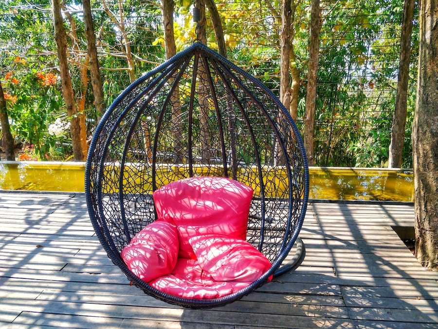 Гамак с розовыми подушками над деревянным полом
