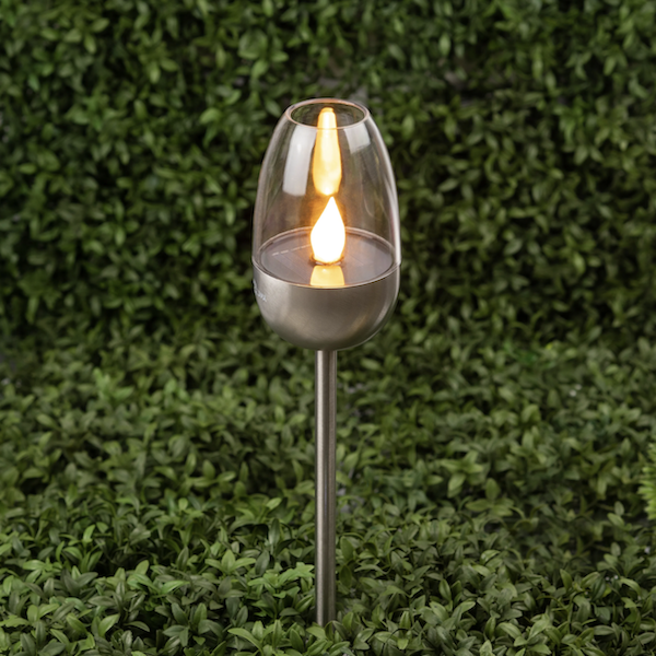 Садовые светильники на шпильках идеально подходят для обозначения дорожек и подсветки клумб Садовый солнечный светильник на фоне темно-зеленых растений