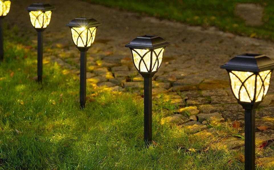 Наличие датчиков движения в светильниках значительно увеличивает экономичность использования Ряд светильников-фонарей в газоне вдоль мощенной дорожки