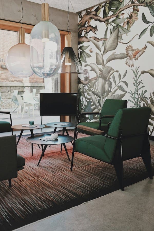 Зеленые кресла, подвесные светильники разных форм, обои с растительным орнаментом, журнальные столики разной высоты
