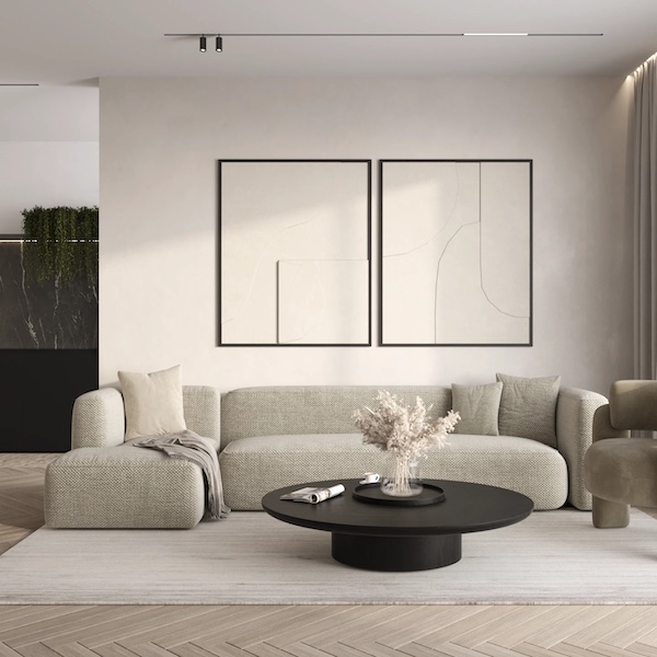 Гостиная в бежевых тонах, черный круглый журнальный стол с вазой, журналом, чашкой, угловой диван, две современные картины на стене