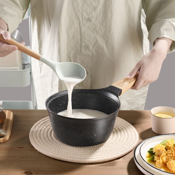 Человек мешает белый соус в кастрюле