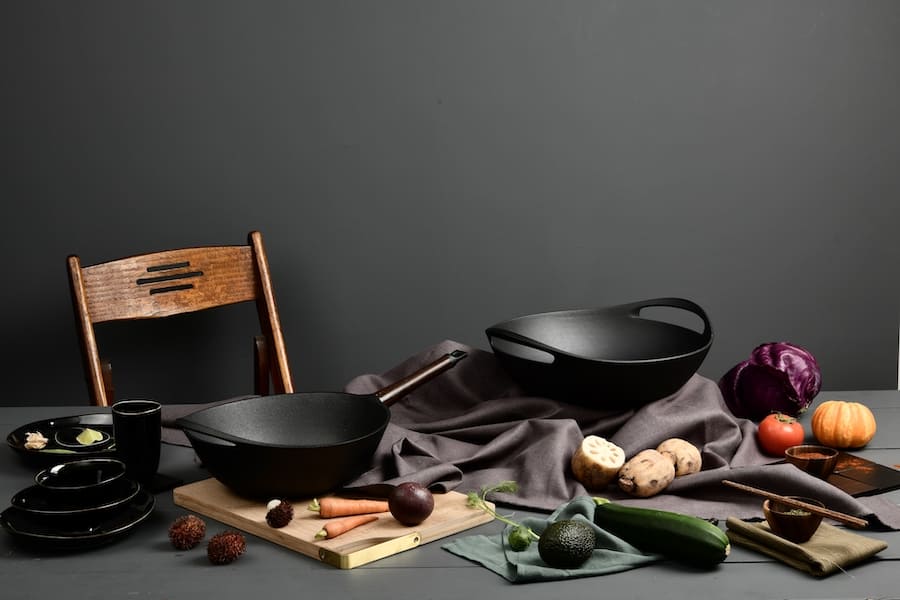 Кастрюли из чугуна и овощи на столе