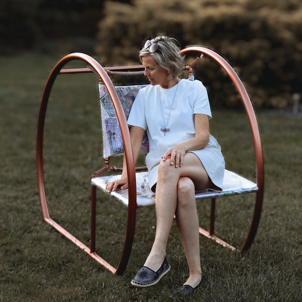 Женщина сидит на дизайнерском стуле в саду
