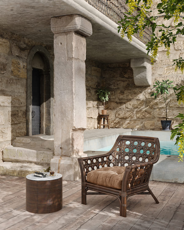 Кресло из ротанга с подушкой на сиденье около бассейна