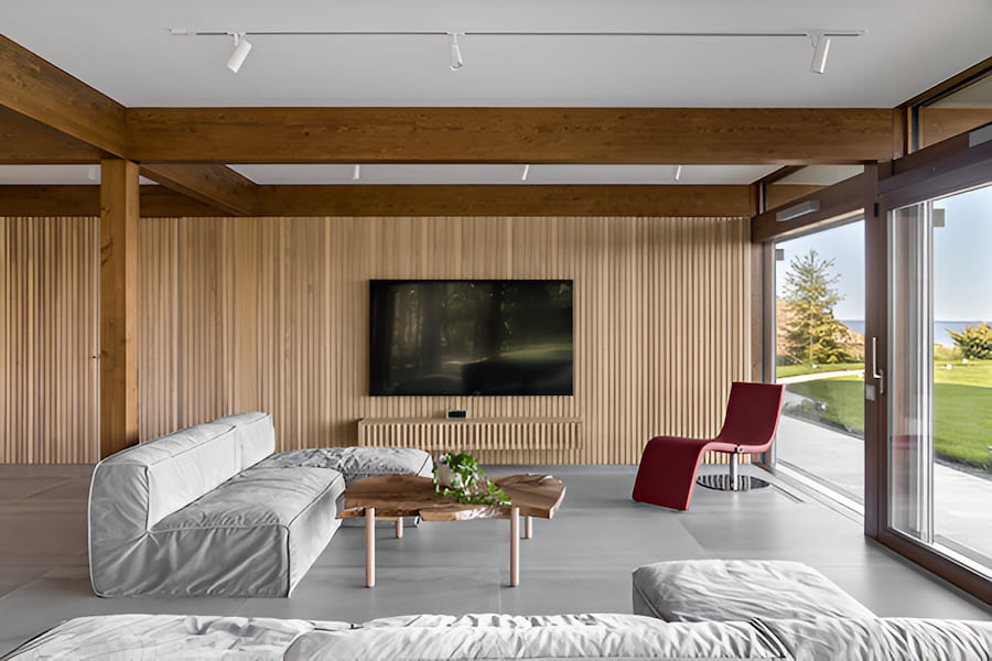 Зона отдыха с прекрасным видом на сад, с функциональной мебелью, расположенной свободно, не перегружает пространство и является продолжением сада Гостиная в доме, стеклянные раздвижные двери на террасу, мягкая мебель, деревянный журнальный столик, кресло-лежак, ТВ-панель