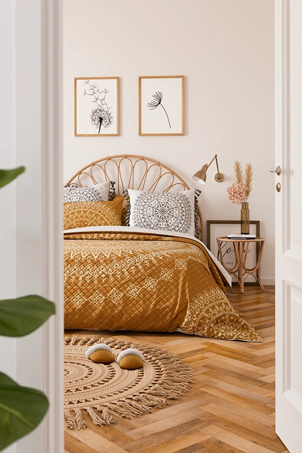 Прикроватное бра располагается на расстоянии 20-30 см от края изголовья, высота установки и направление света влияют на функциональность и визуальное восприятие Пространство спальни, кровать, бра, два постера, вязаный коврик, тапочки, тумбочка и изголовье кровати из ротанга, ваза с сухоцветами