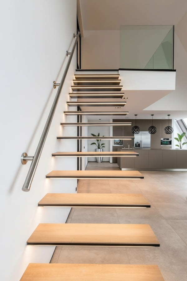 Спальня, двуспальная кровать, в изголовье зеленая стена, две тумбочки, картина на стене, корзина с полотенцем, два подвесных светильника и трековая система освещения