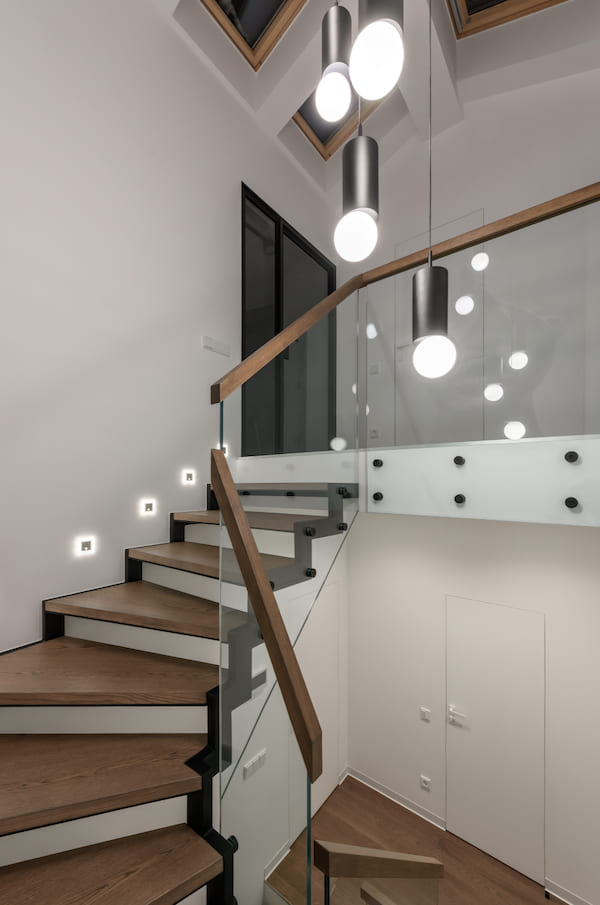 Спальня, двуспальная кровать, в изголовье зеленая стена, две тумбочки, картина на стене, корзина с полотенцем, два подвесных светильника и трековая система освещения