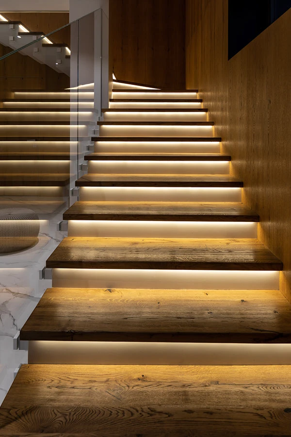 Спальня, двуспальная кровать, в изголовье зеленая стена, две тумбочки, картина на стене, корзина с полотенцем, два подвесных светильника и трековая система освещения