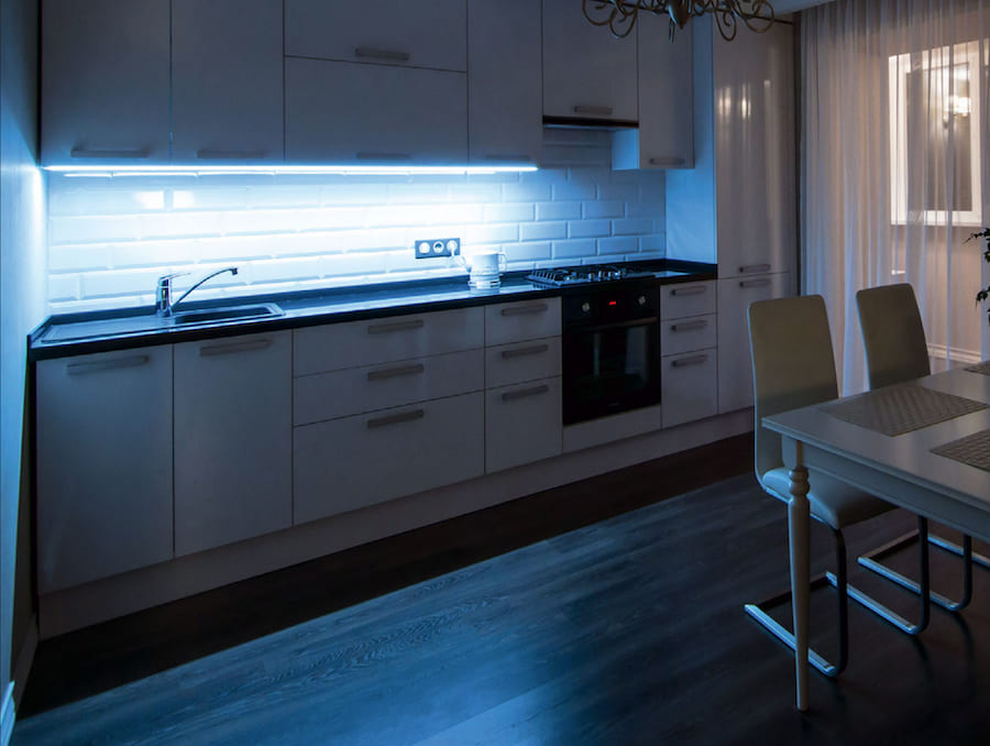 Пространство кухни, стол, два стула, окно за занавеской, светящаяся LED лента