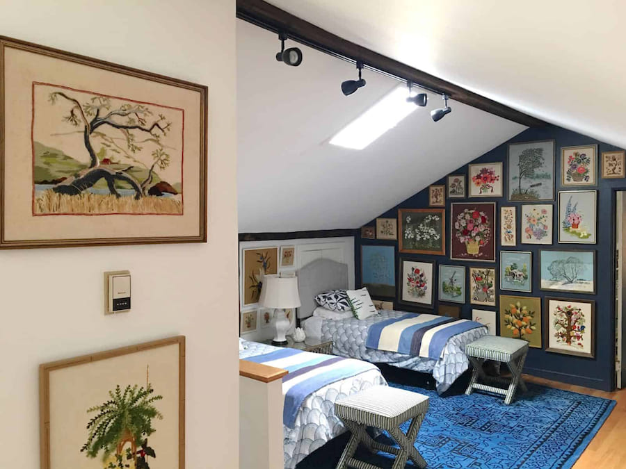 Разнонаправленные споты несут задачу общего освещения и акцентную функцию Детская комната со скошенными потолками, картины на стенах, две кровати, две табуретки, тумбочка с настольной лампой